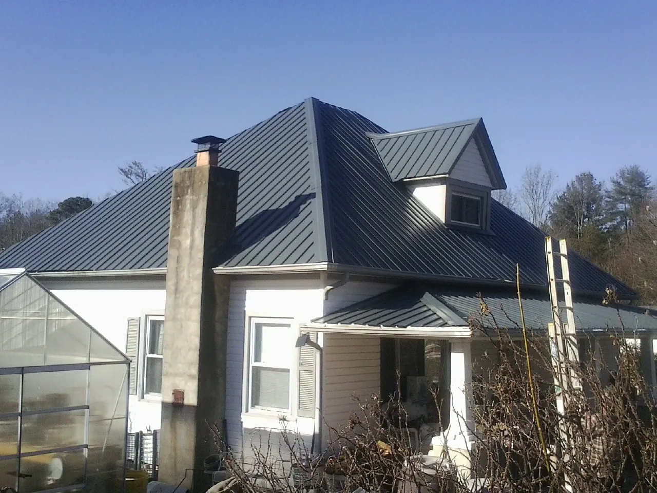 Dark blue standing seam metal roof on a white farmhouse with dormer — Slate & Tile Roof Repair by Roofing Brothers in Phillipsburg