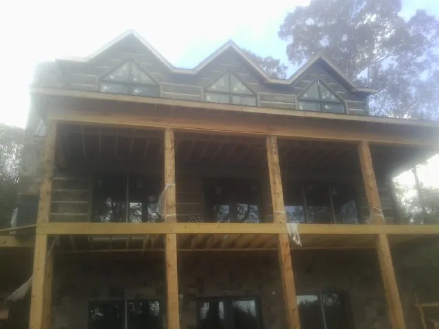 Dormers and porch framing on a large log home under construction — Roof Coating work by our crew in Phillipsburg
