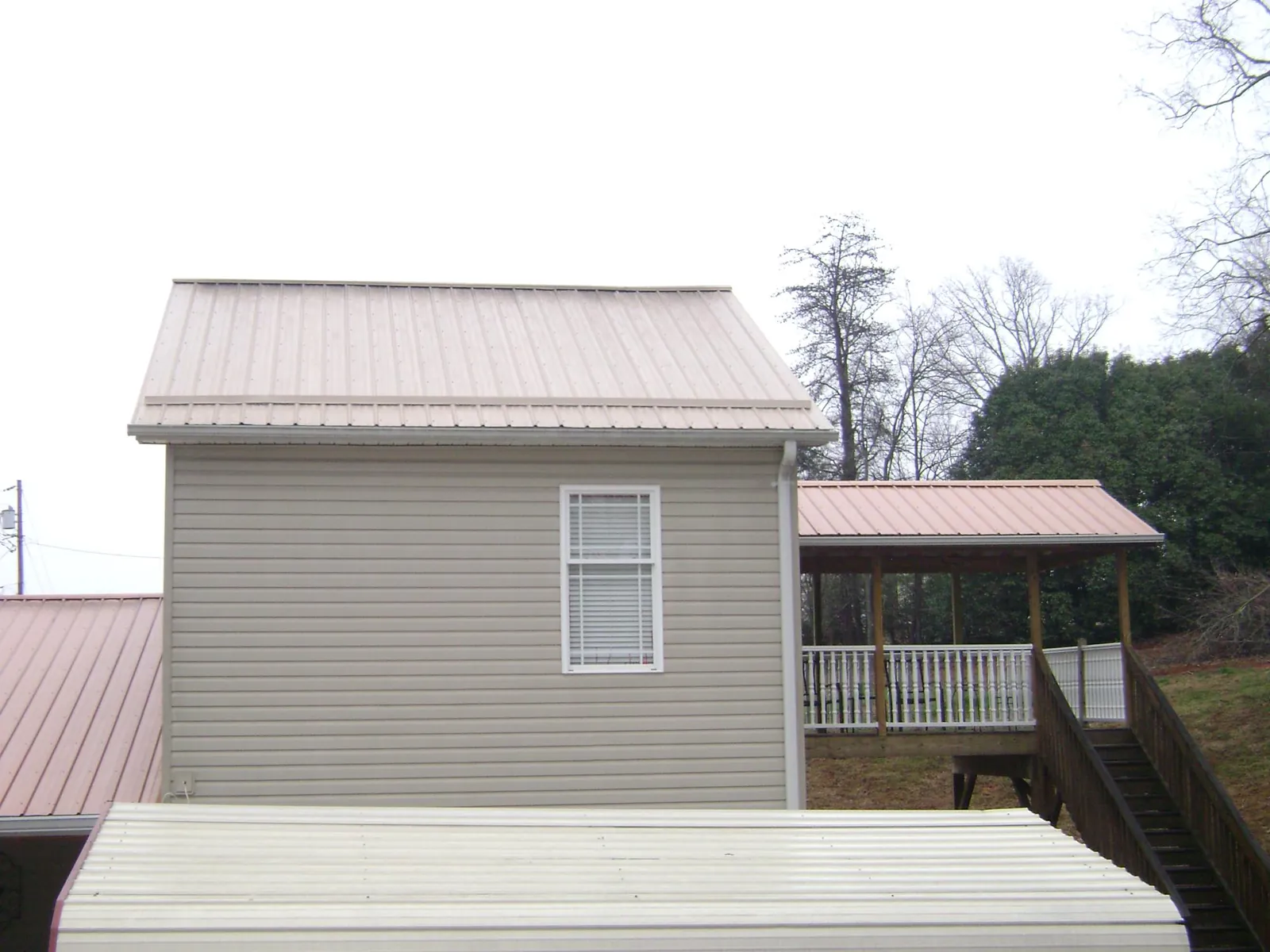 Tan metal roofs on a two story addition and attached porch, from a Roof Replacement job in Phillipsburg