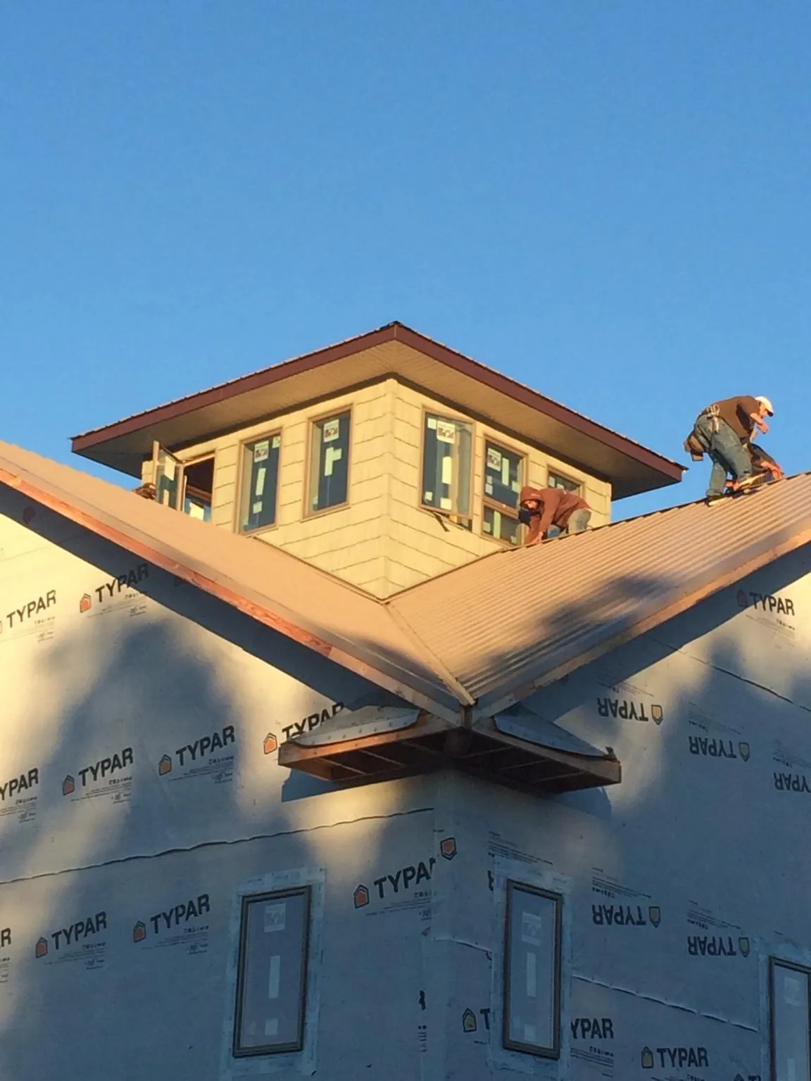 Roofers working around a rooftop cupola on a new metal roof at sunset — Roof Waterproofing in Phillipsburg by Roofing Brothers